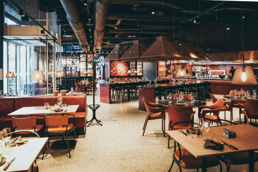 Dining room of a modern restaurant with an open kitchen behind the bar