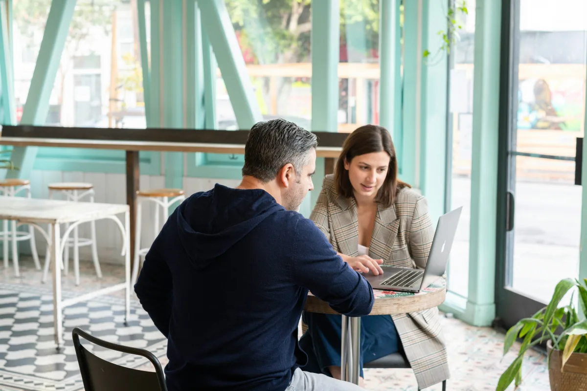 A partner walking a café owner through the platform on a laptop at their table